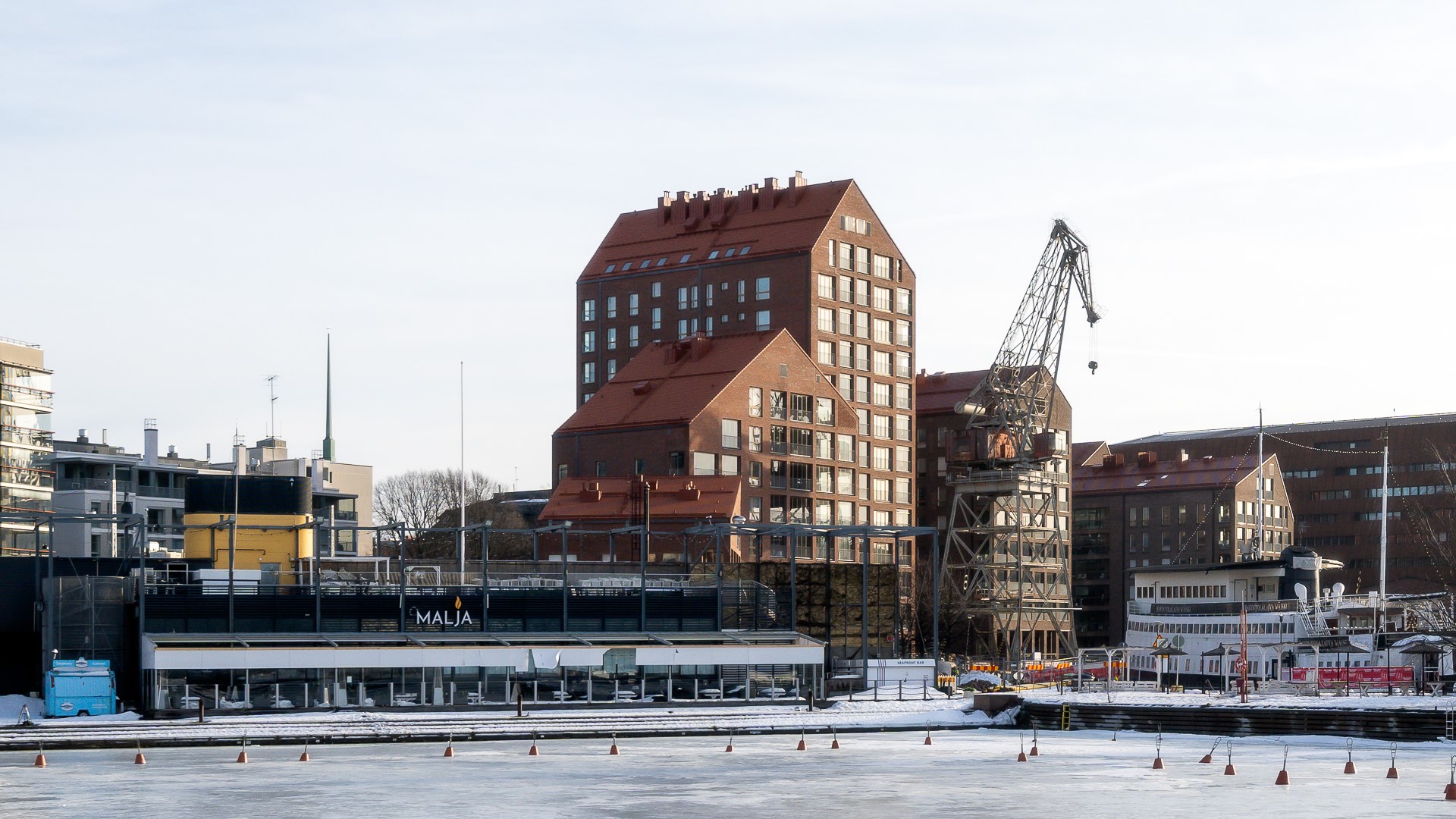 Harjakattoiset punatiiliset asuinrakennukset sopivat alueen historialliseen arkkitehtuuriin: rannan vanhat nosturit muistuttavat alueen teollisesta historiasta.