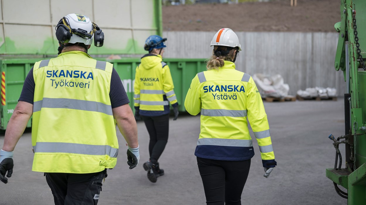 Kolme työntekijää kävelemässä työmaalla turvavarusteissa.