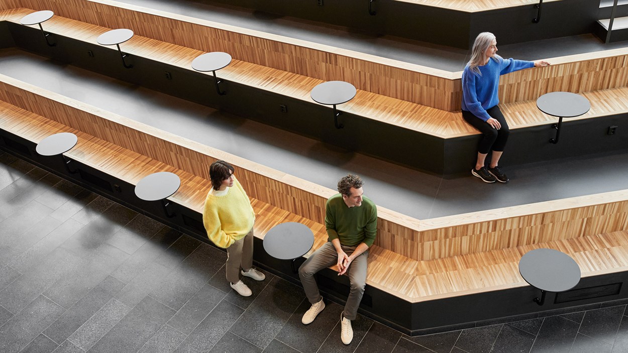 henkilöitä seisoo ja istuu ruotsalaisen toimistotalon istuskeluportailla