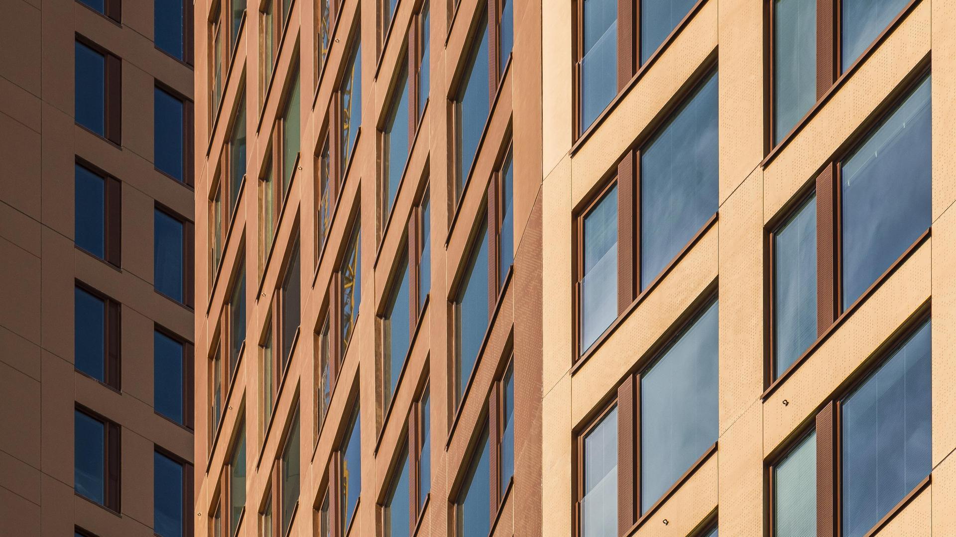 Lähikuva pronssinhohtoisten tornitalojen julkisivuista, joissa on paljon ikkunoita. 