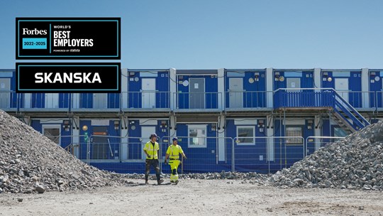 Työntekijöitä kävelemässä työmaakoppien edessä.